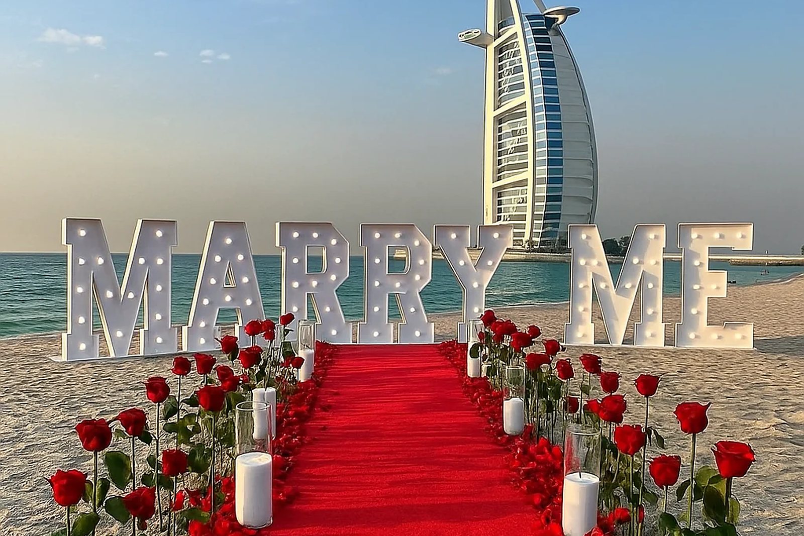 MARRY ME letters and a rose-lined carpet on the beach by the Burj Al Arab